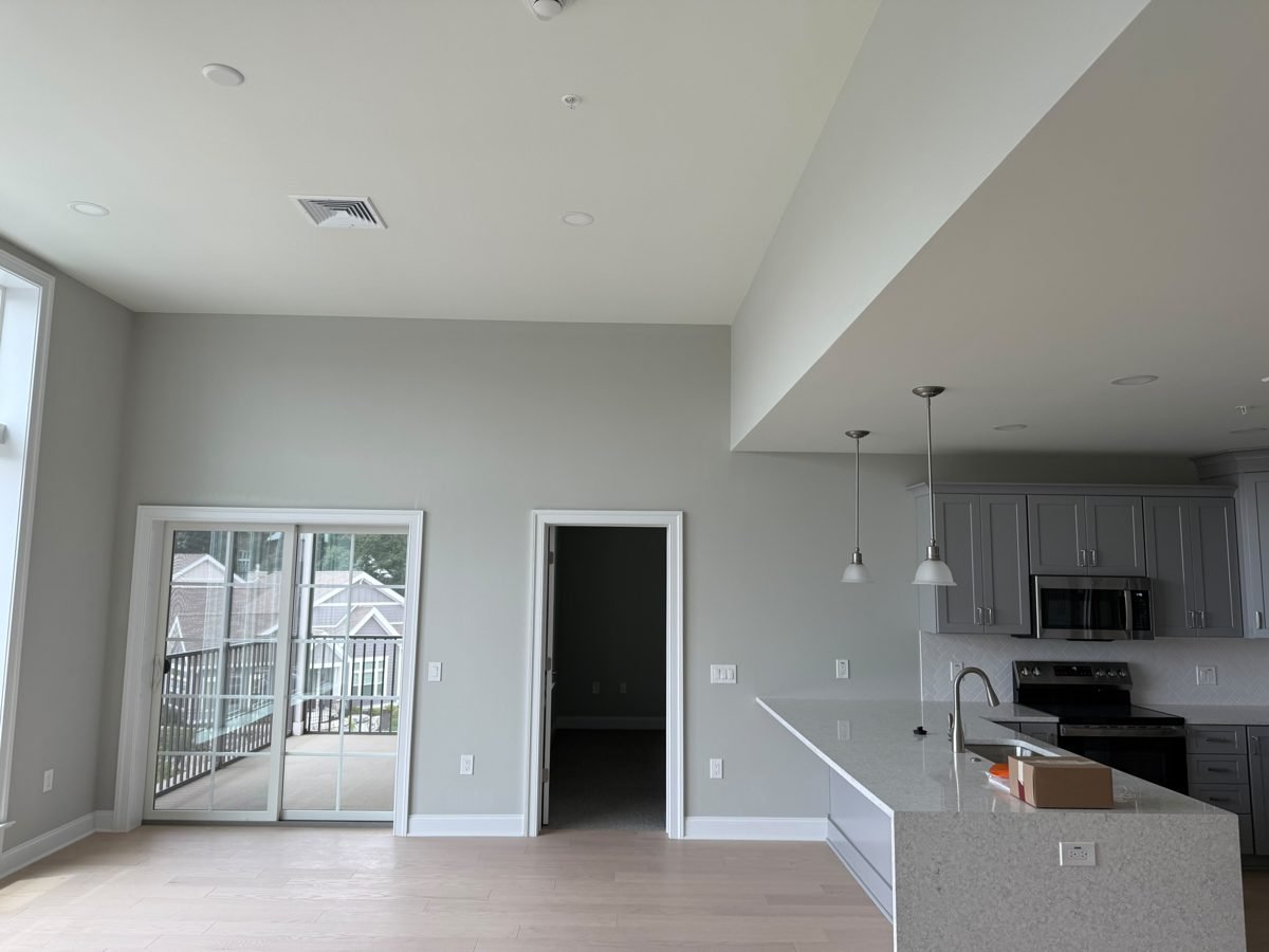 Open-plan kitchen and living area with an island, gray cabinets, sliding doors and light floors